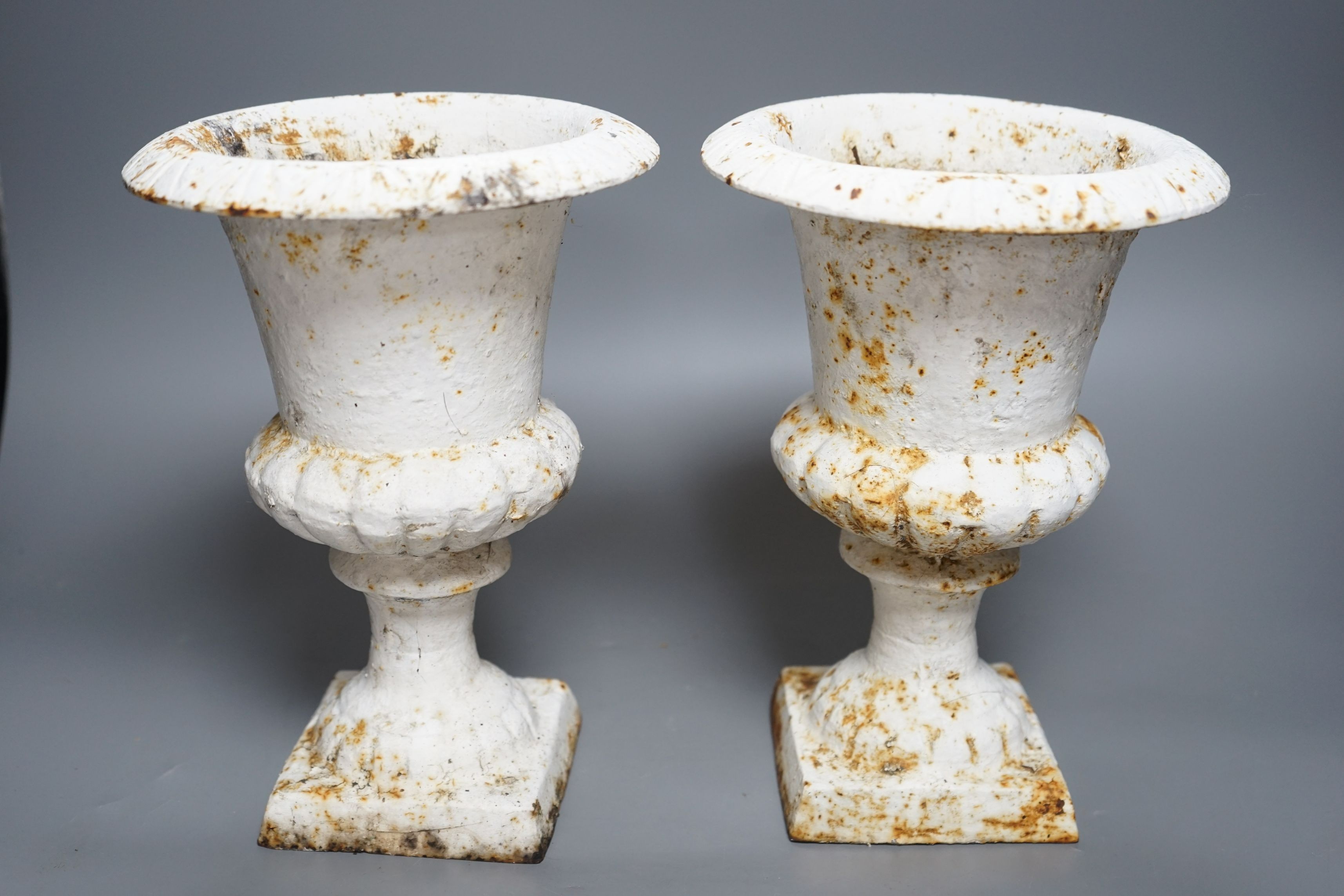 A pair of small white painted cast-iron campana urns, 25cms high